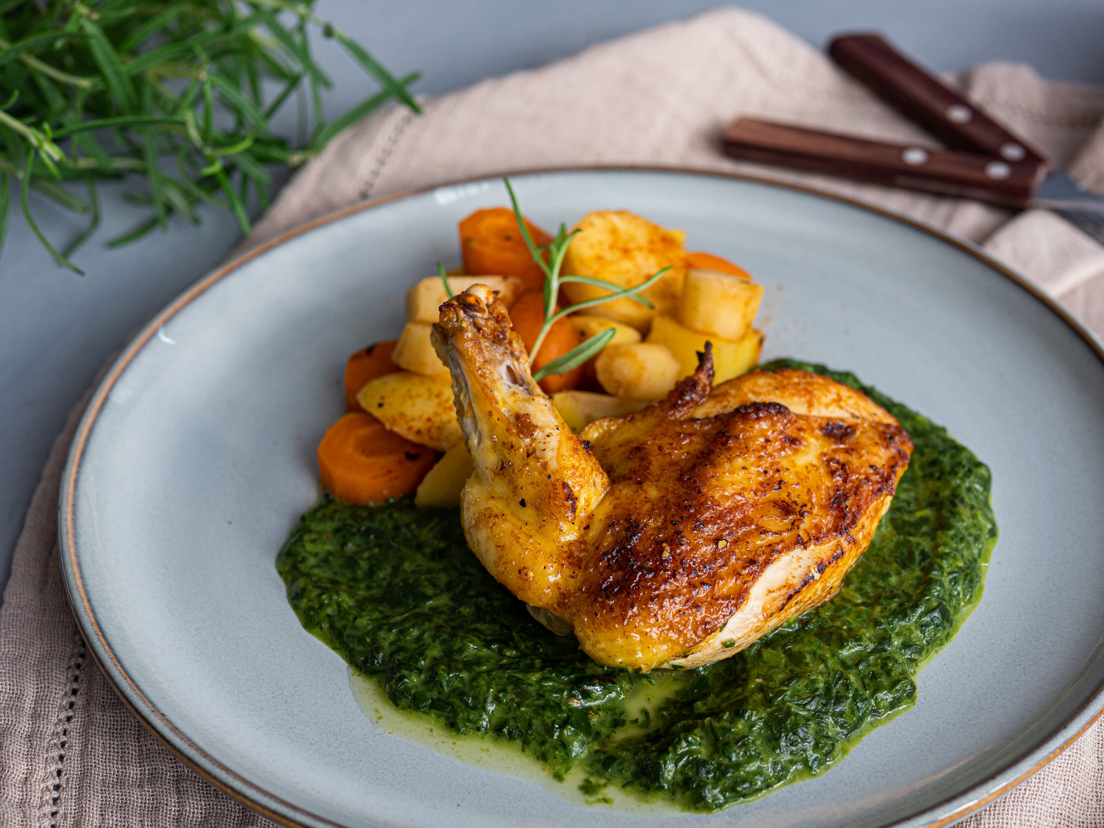 Maishähnchenbrust in Orangen-Rum-Marinade mit Gemüse und Rahmspinat auf einem Teller angerichtet.