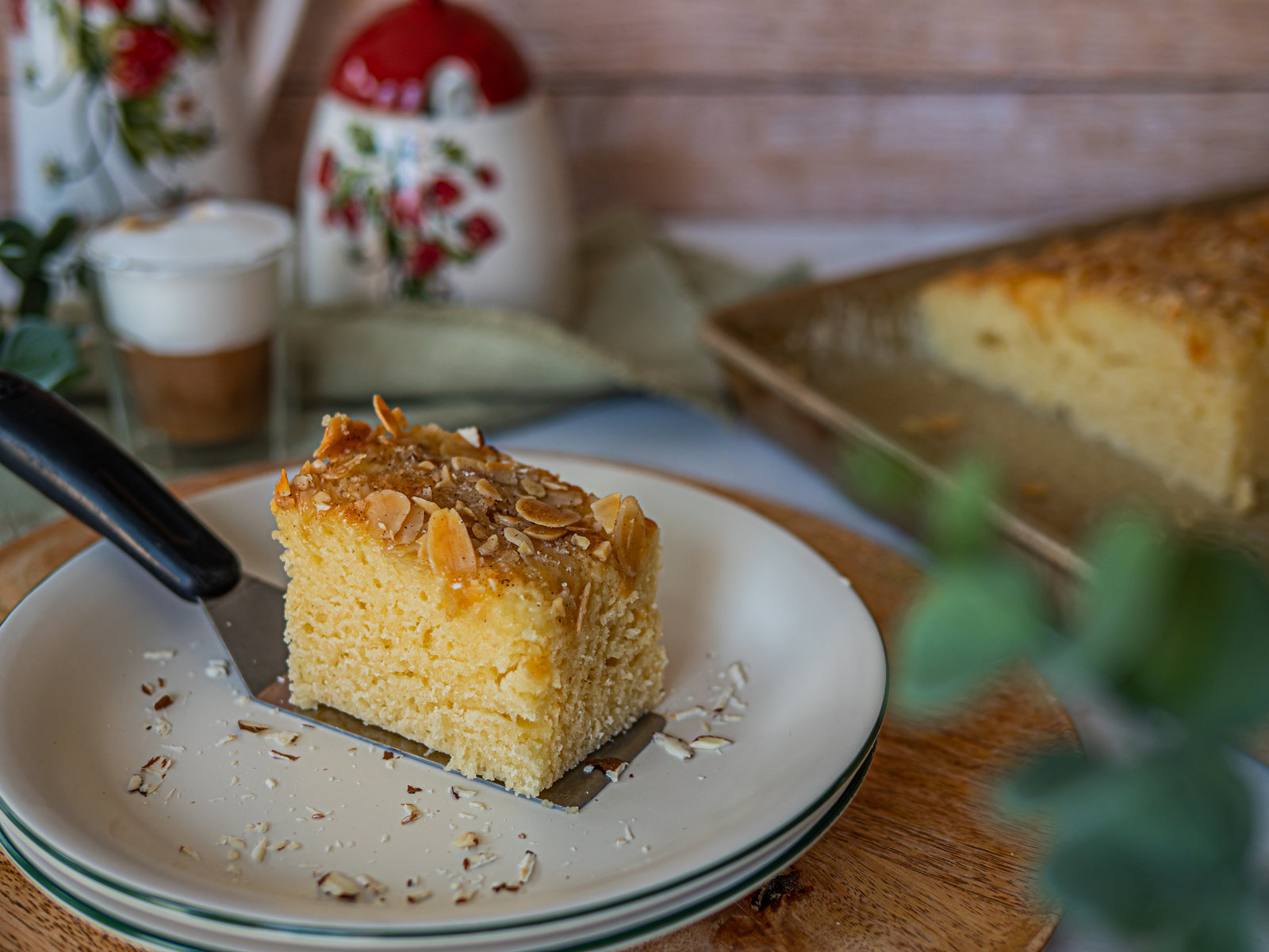 Ein Stück Tassenkuchen mit Mandeln und Sahne auf einem Teller.