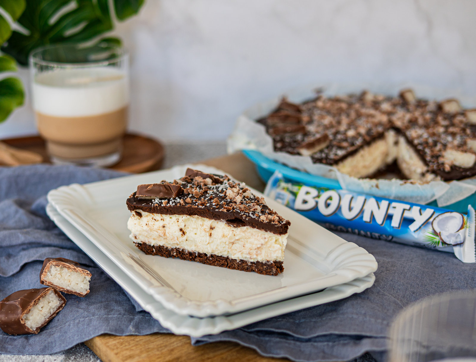 Eine angeschnittene No-Bake Bounty-Tarte mit Kokosfüllung und Schokoladenglasur, dekoriert mit Bounty-Stücken.
