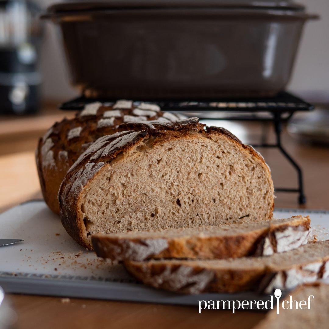 Ein frisch gebackenes Roggen-Dinkelbrot, angeschnitten, auf einem Holzbrett.