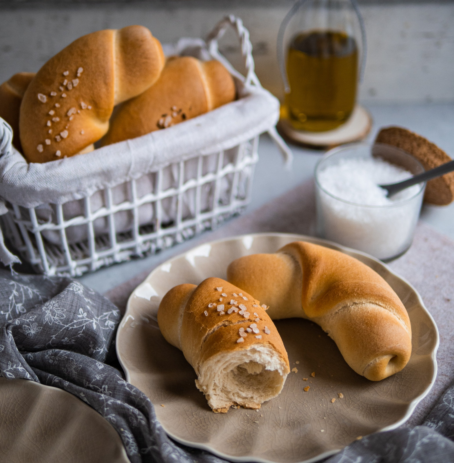 Frisch gebackene salzige Kipferl mit Olivenöl, bestreut mit grobem Salz und Kümmel, auf einem Backblech.