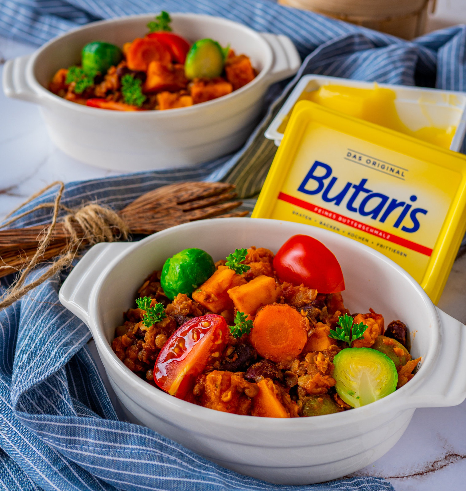 Eine Schale mit vegetarischem Chili Con Carne, garniert mit frischen Kräutern und Brot daneben.