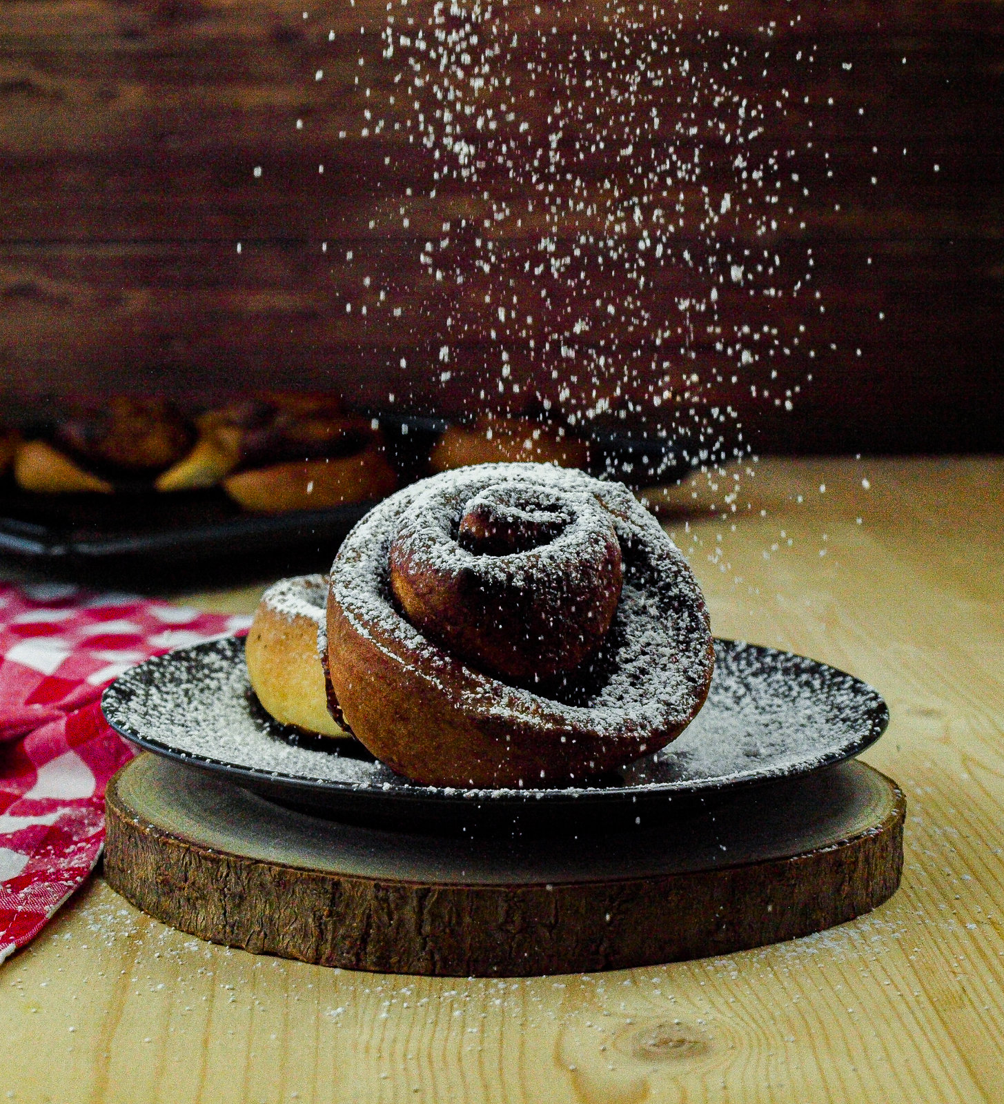 Nahaufnahme von frisch gebackenen, mit Puderzucker bestreuten Schokoschnecken auf einem Backblech.