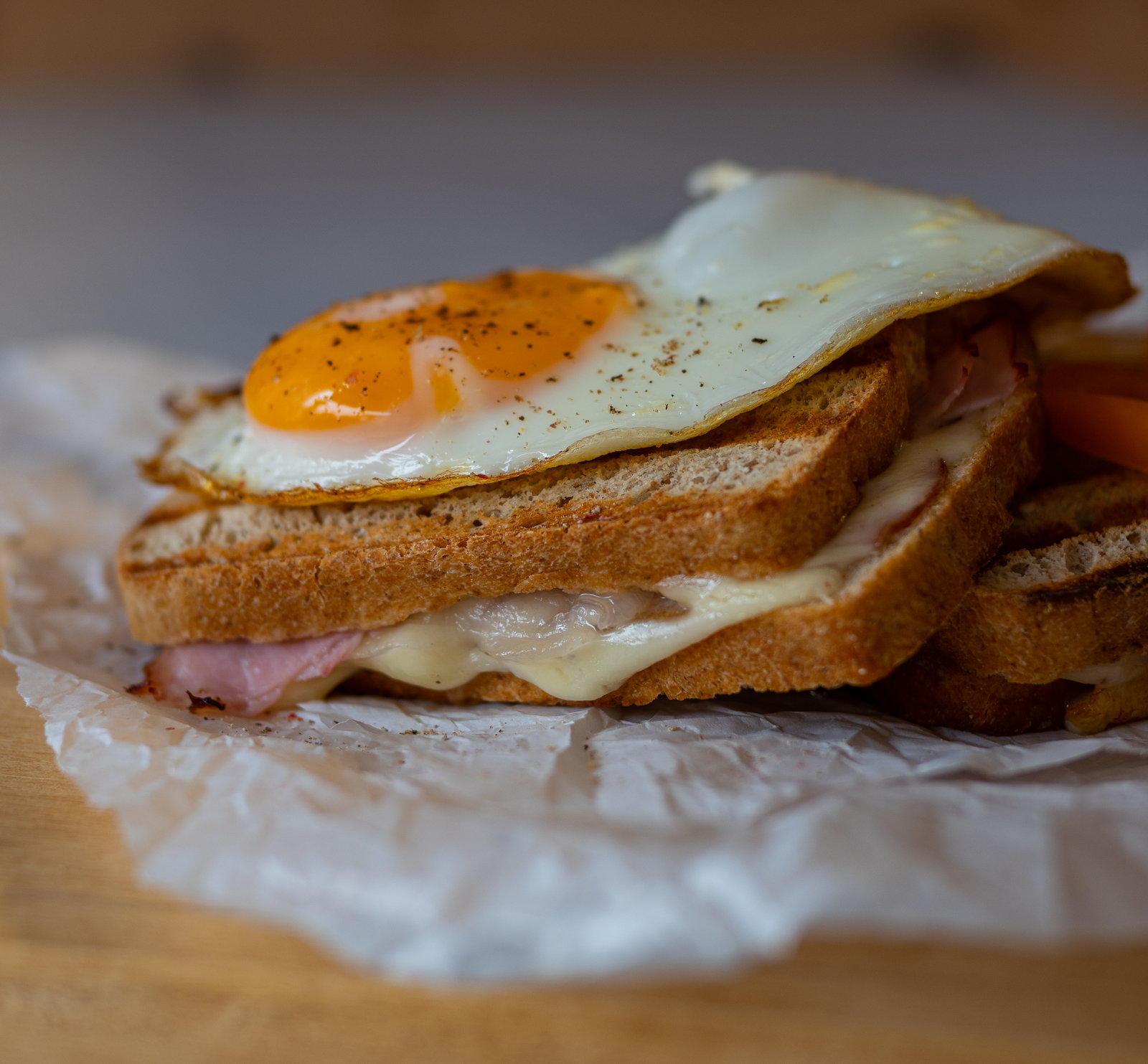 Zwei Croque Madame auf Tellern, belegt mit Spiegelei und garniert mit frischem Gemüse.