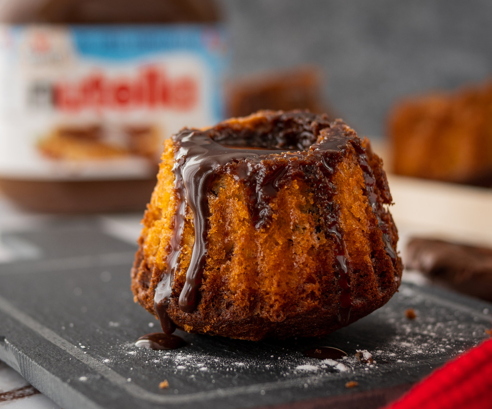 Mehrere Mini Marmor Gugelhupfe, teilweise mit Nutella®-Glasur, auf einem Teller angerichtet.