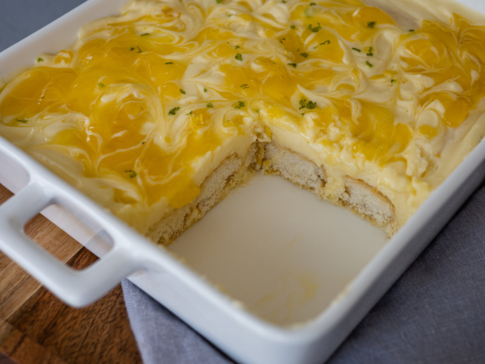 Ein Zitronen-Tiramisu in einer Auflaufform, verziert mit Lemon Curd und Zitronenschale.