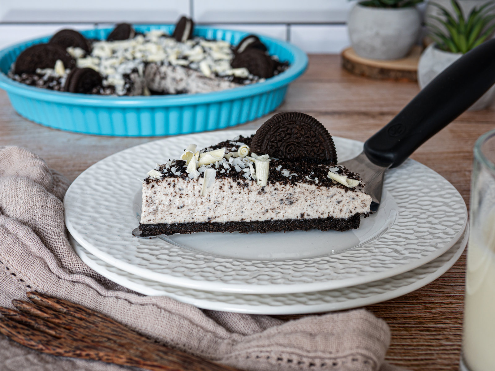 Eine angeschnittene No Bake Oreo Tarte mit Keksboden, heller Creme und Oreo-Keks-Stückchen sowie weißer Schokolade als Dekoration.