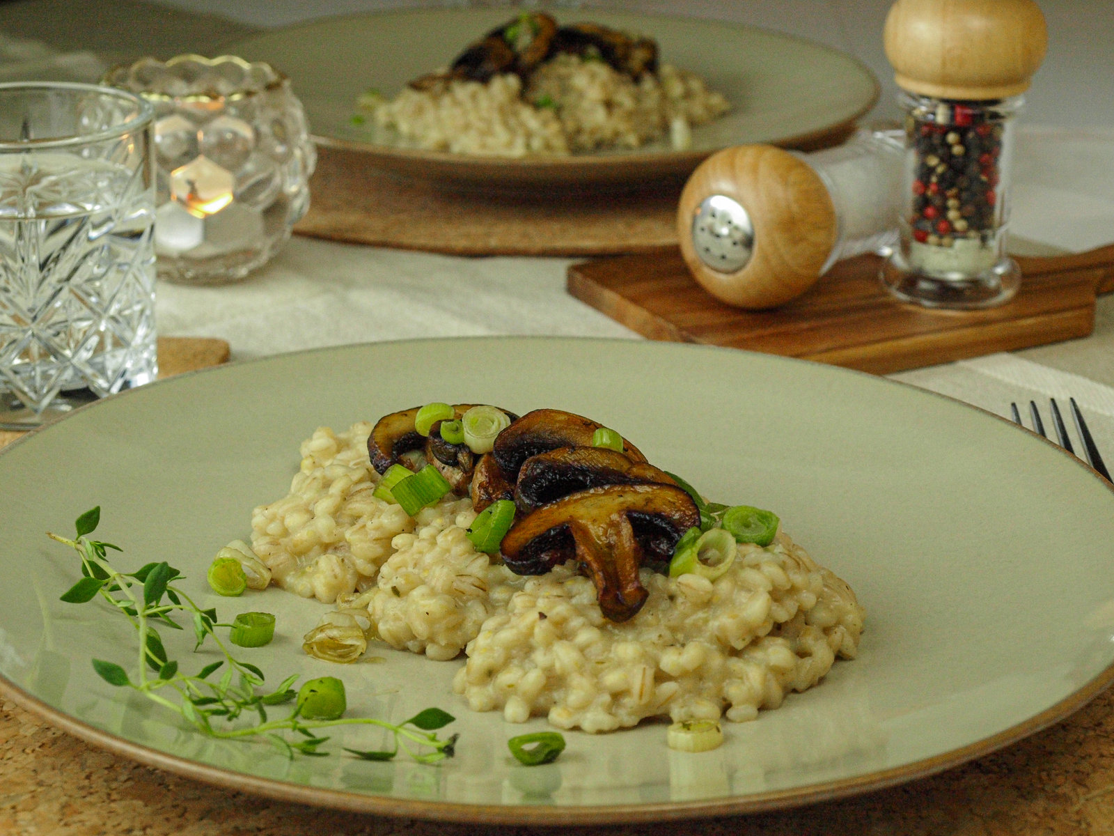 Cremiges Gersten-Risotto mit gebratenen Champignons und frischen Kräutern in einer Schale angerichtet.