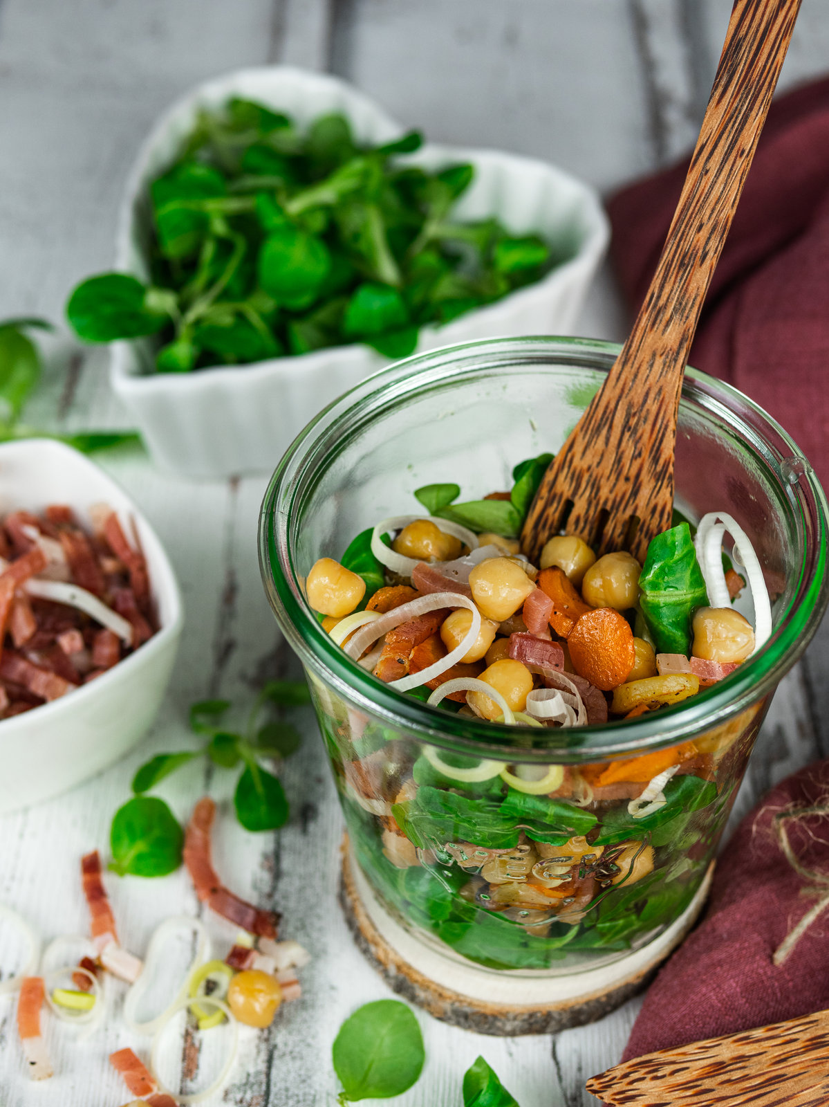 Warmer Kichererbsensalat mit Speck und Vogerlsalat in einer Schale angerichtet