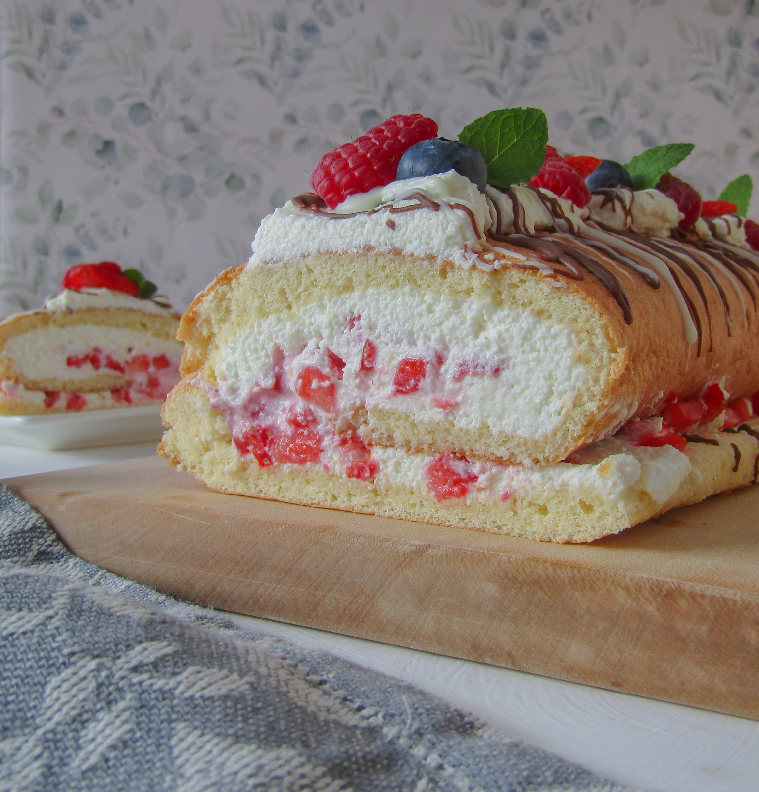 Eine aufgeschnittene Erdbeer-Roulade mit Quarkcreme und frischen Erdbeeren