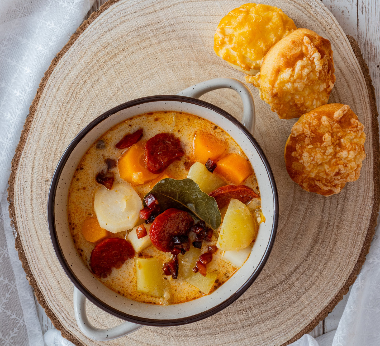 Eine Schale ungarische Kartoffelsuppe mit Kolbász und saurer Sahne, garniert mit frischen Kräutern.