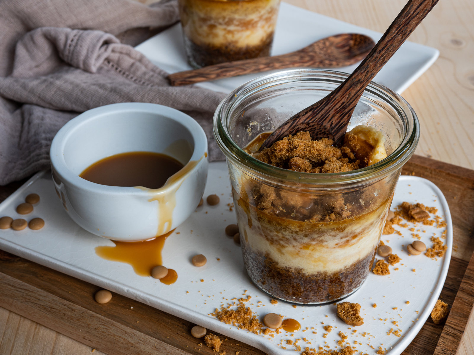 Vier Gläser mit Karamell-Käsekuchen, bestreut mit Rohrzucker und Karamelldrops.