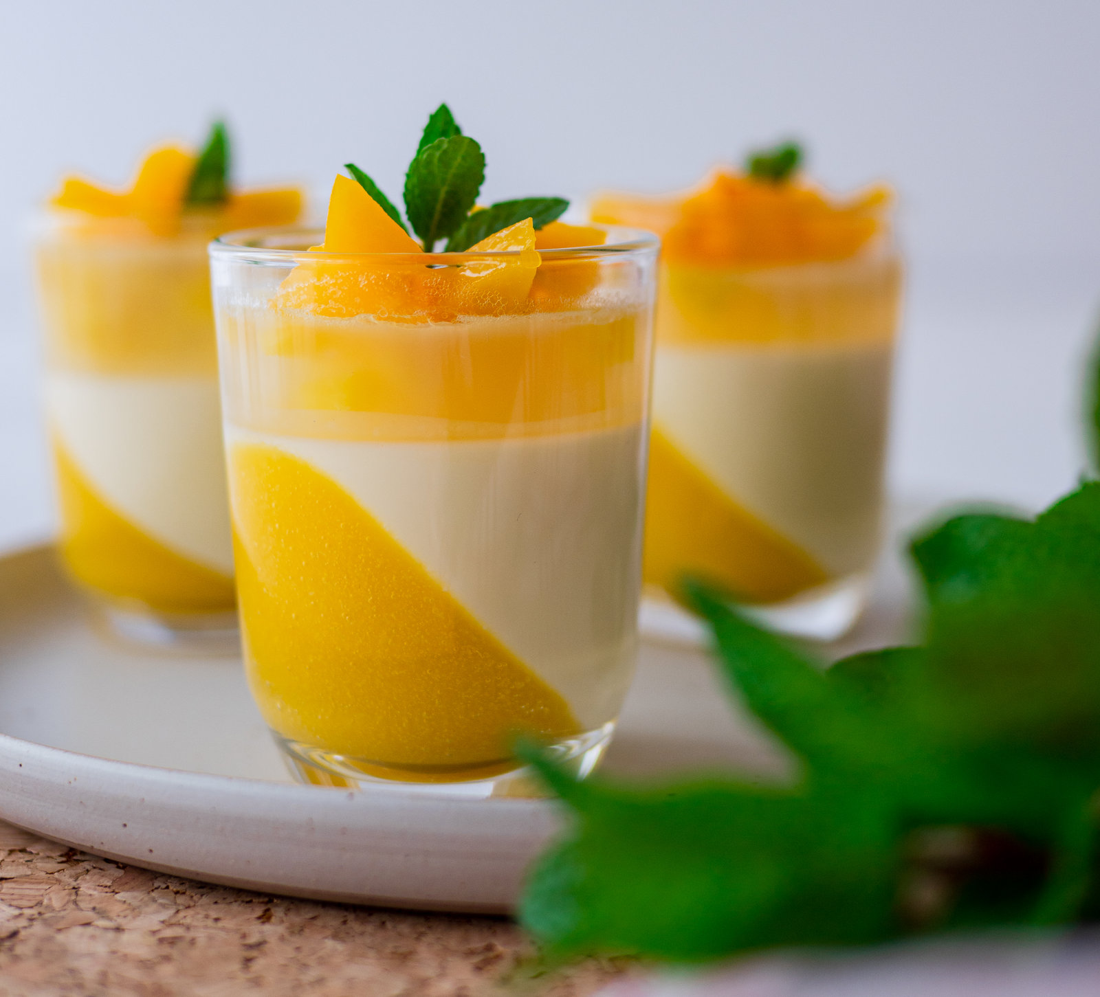 Panna Cotta mit Aprikosen in Gläsern, geschichtet mit Gelee und Tortenguss, dekoriert mit Aprikosenwürfeln.