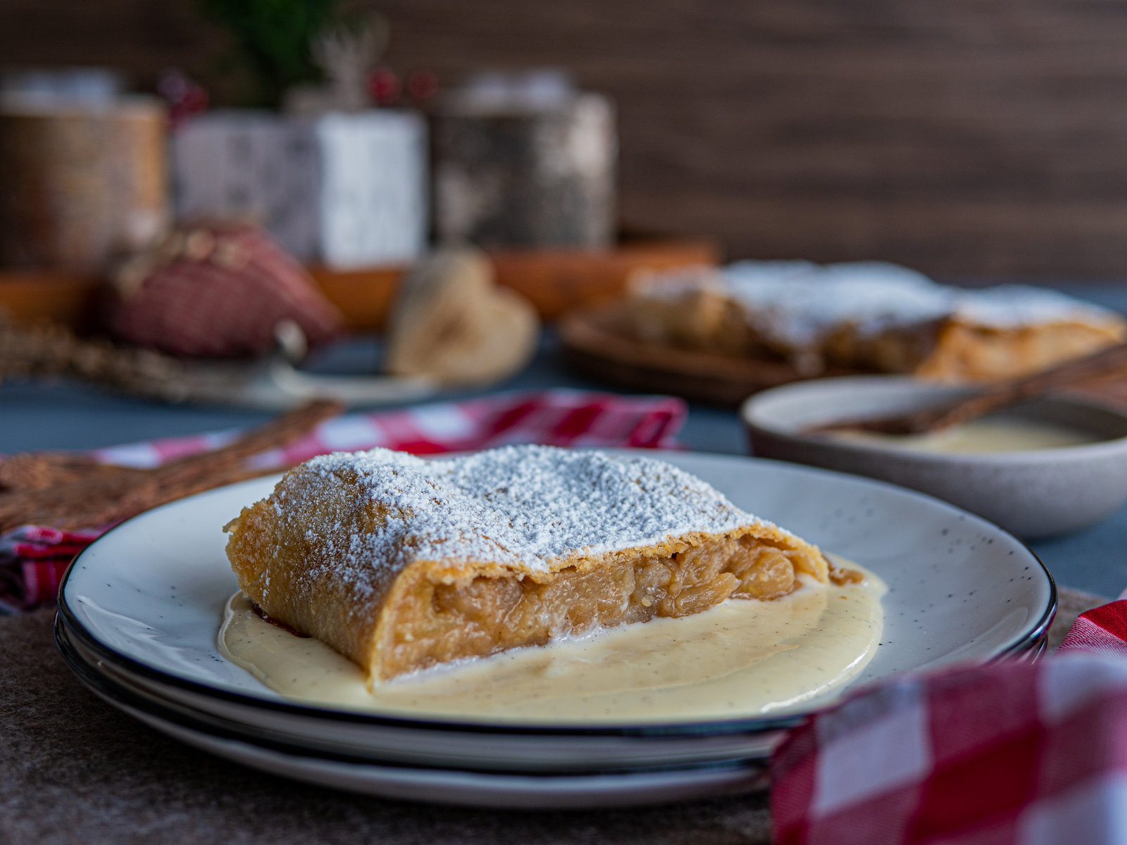 Ein Stück Tiroler Apfelstrudel mit Vanillesauce auf einem Teller