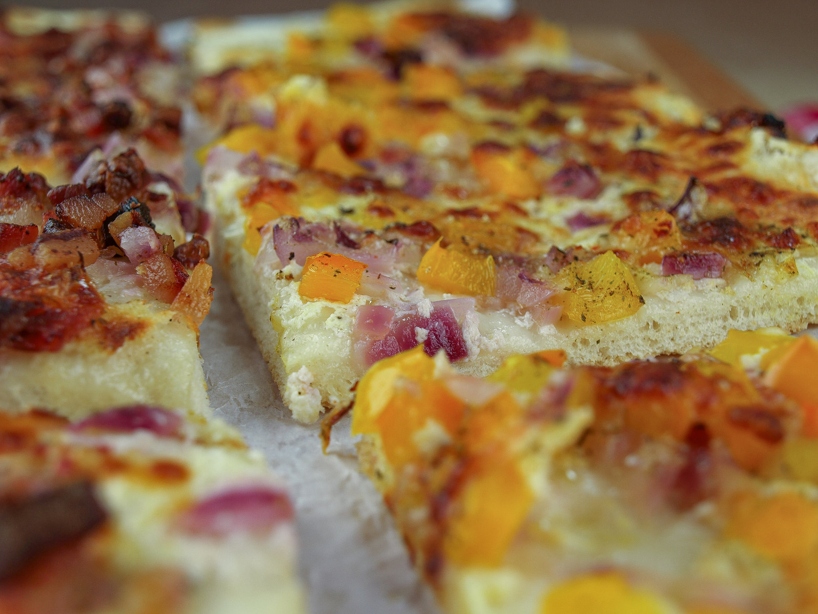 Ein frisch gebackener ungarischer Flammkuchen mit verschiedenen Belägen wie Speck, Zwiebeln und Paprika.