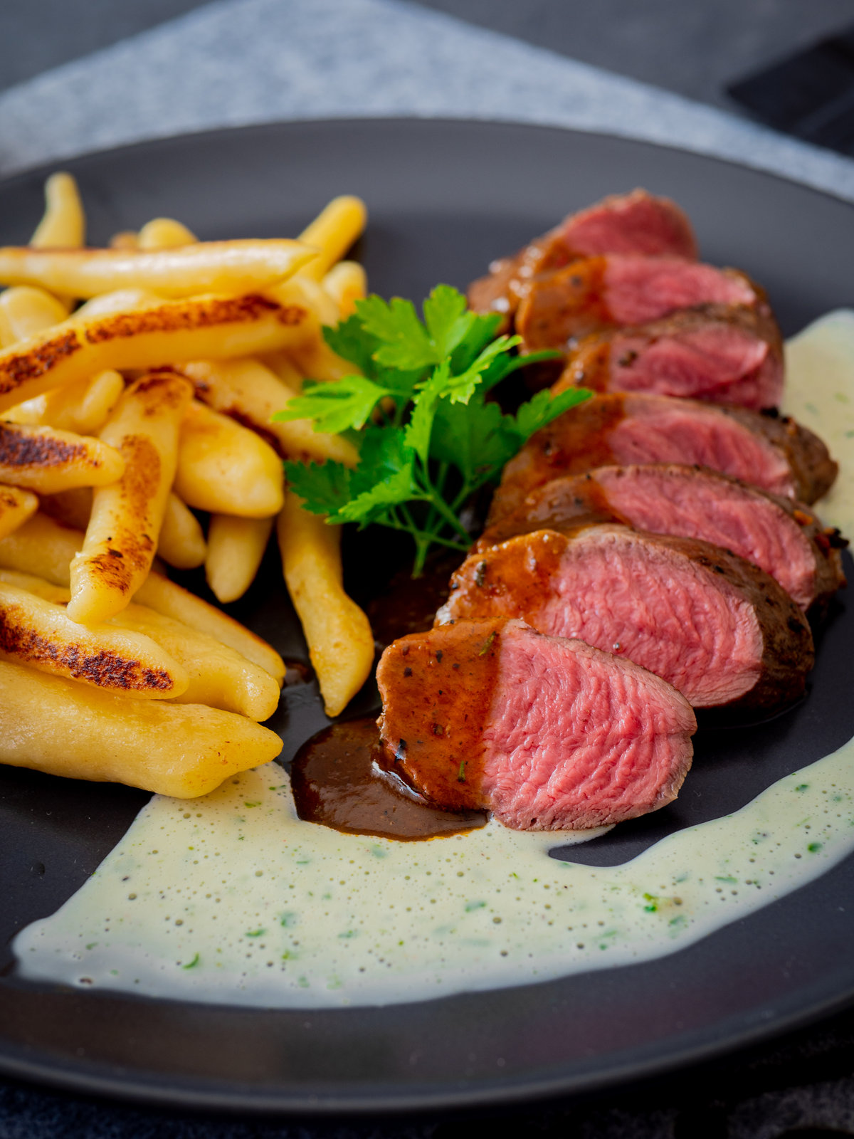 Rehlende in Scheiben geschnitten, angerichtet mit Schupfnudeln, Liebstöckelsauce und brauner Jus.