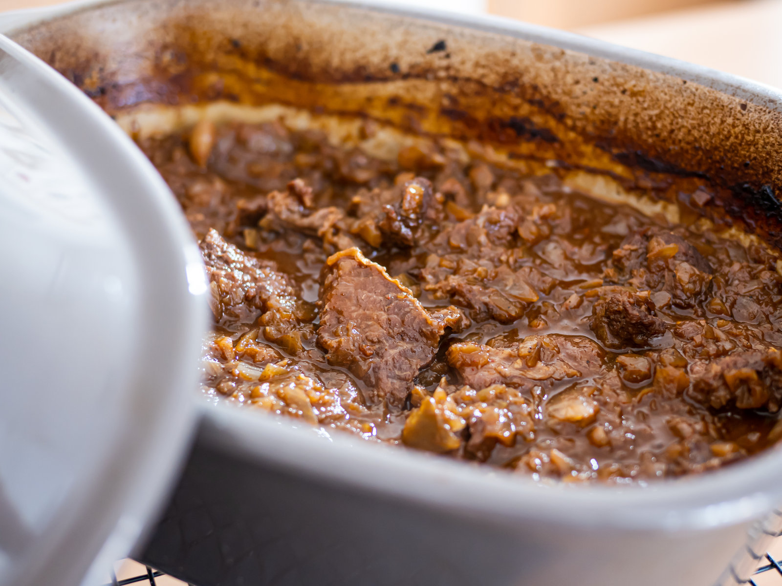 Ein dampfendes Rindergulasch mit viel Sauce und Zwiebeln in einem Ofenmeister.