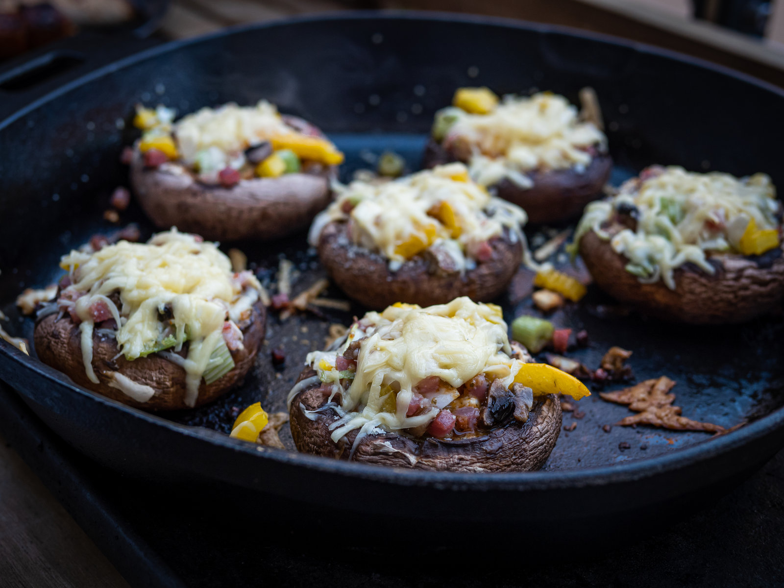 Gefüllte Champignons mit Käse überbacken in einer gusseisernen Pfanne.