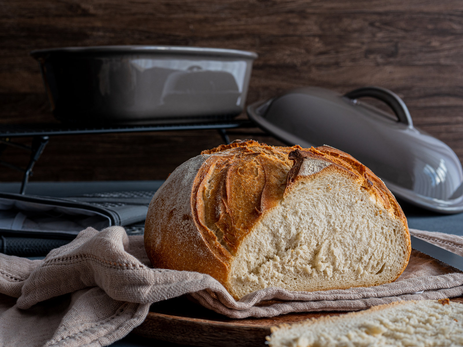 Ein frisch gebackenes, goldbraunes Weißbrot mit eingeschnittener Kruste, das auf einem Holzbrett liegt.