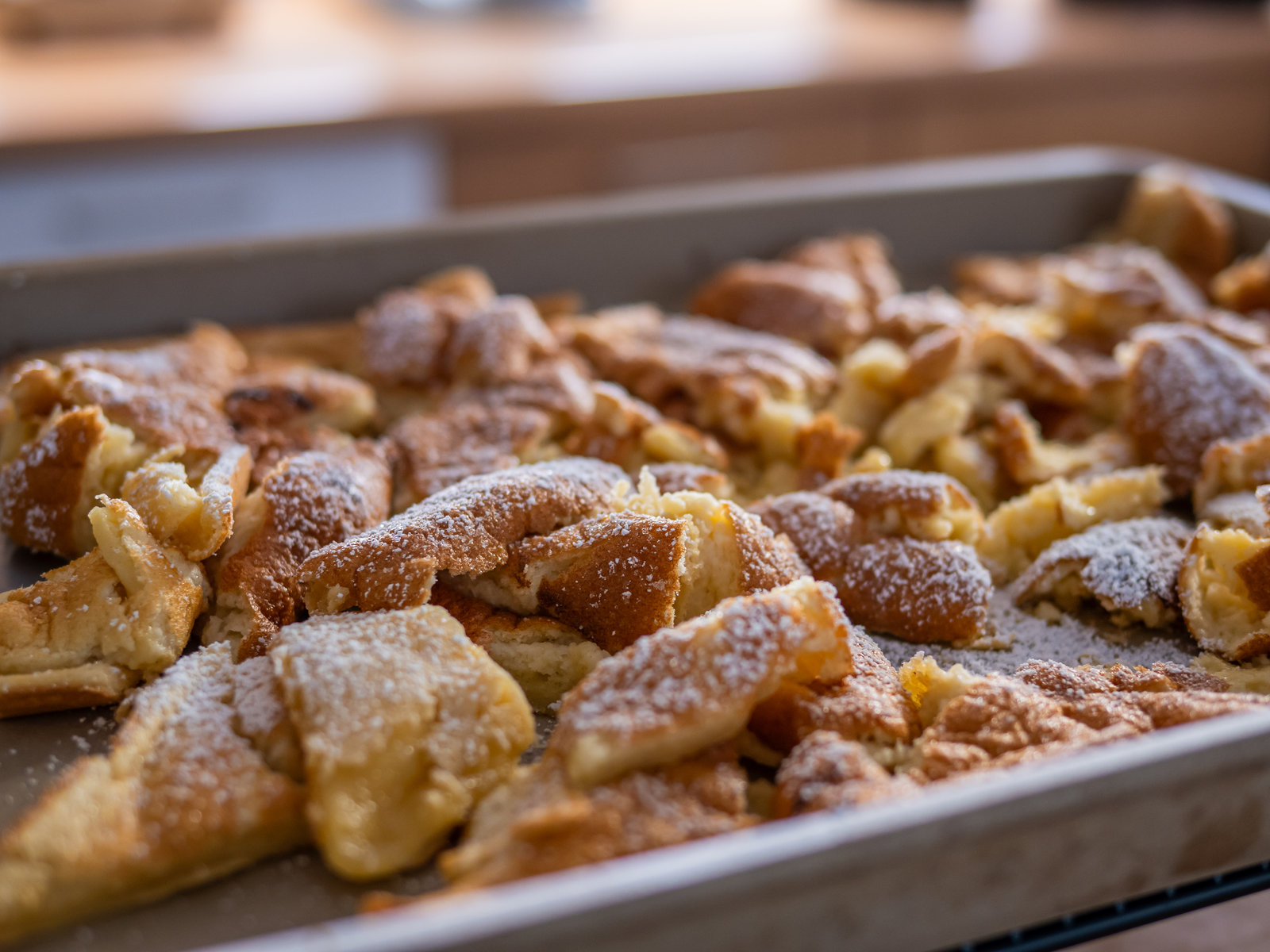 Ein goldbrauner Kaiserschmarrn, bestreut mit Puderzucker, serviert mit Apfelmus und Preiselbeermarmelade.
