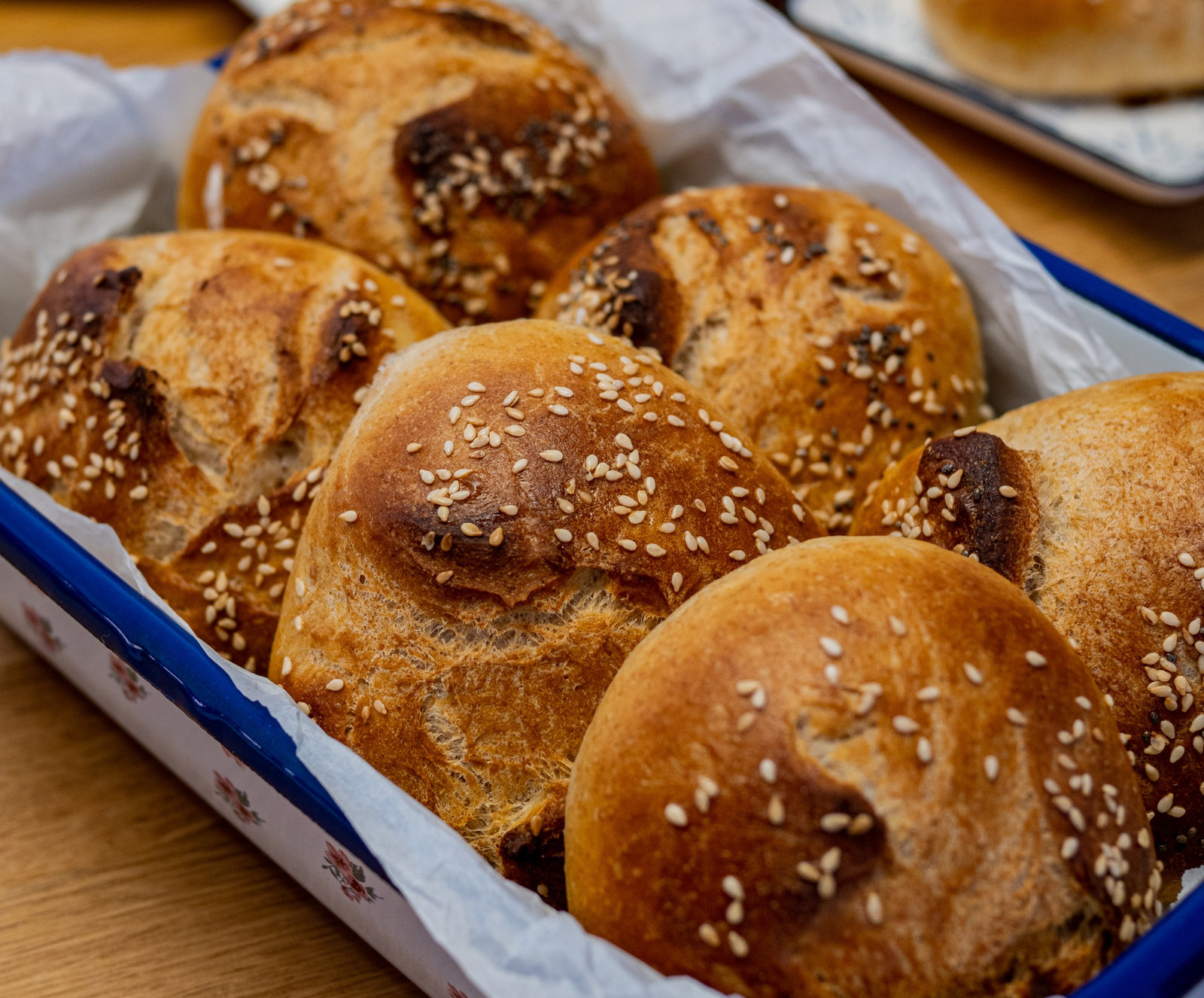 Frisch gebackene Buttermilch-Dinkel-Brötchen auf einem Backblech, bestreut mit Sesam und Mohn.