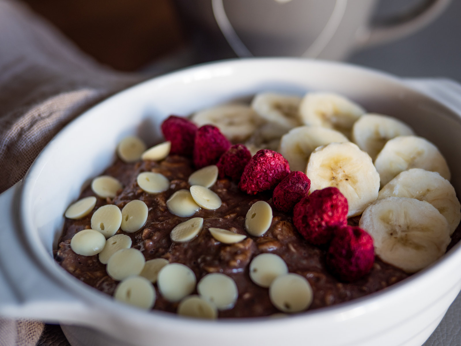 Schokobrei mit Bananenscheiben, Himbeeren und weißen Schokodrops in einer Schale