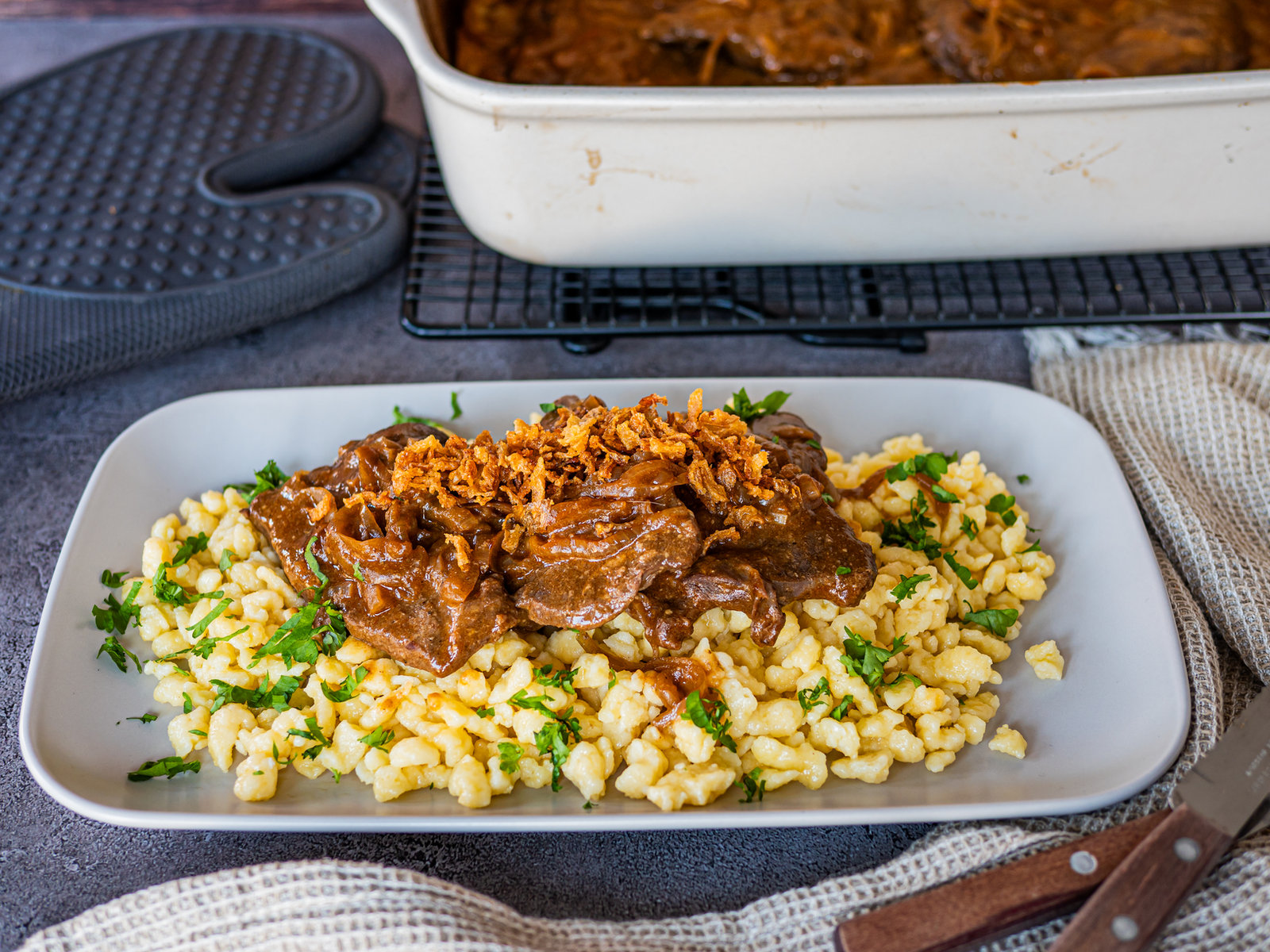 Tiroler Zwiebelrostbraten mit Zwiebelringen und Soße in einer Ofenhexe