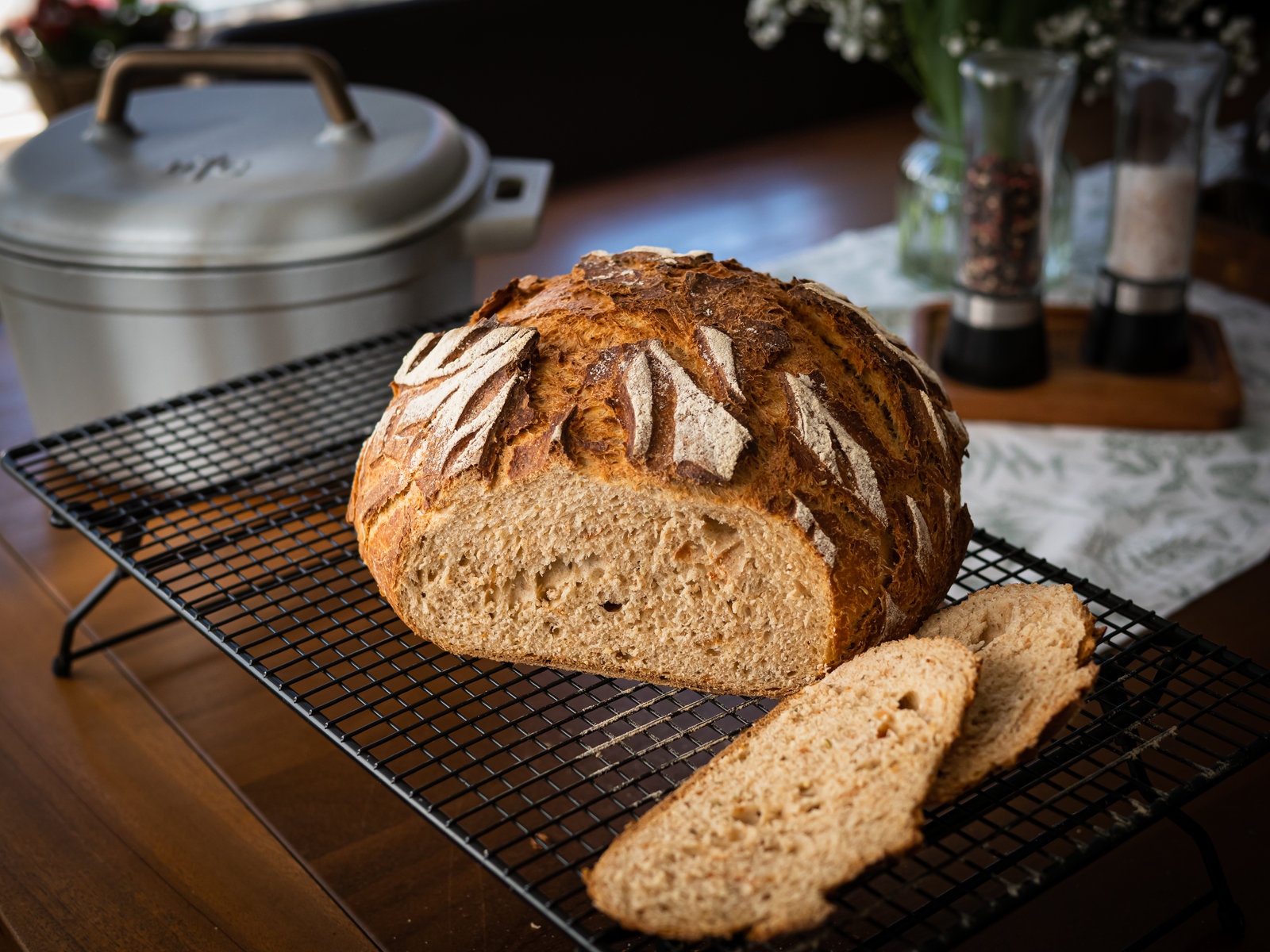 Ein frisch gebackenes, rundes Dinkelbrot mit eingeschnittener Kruste, das auf einem Gitterrost liegt.