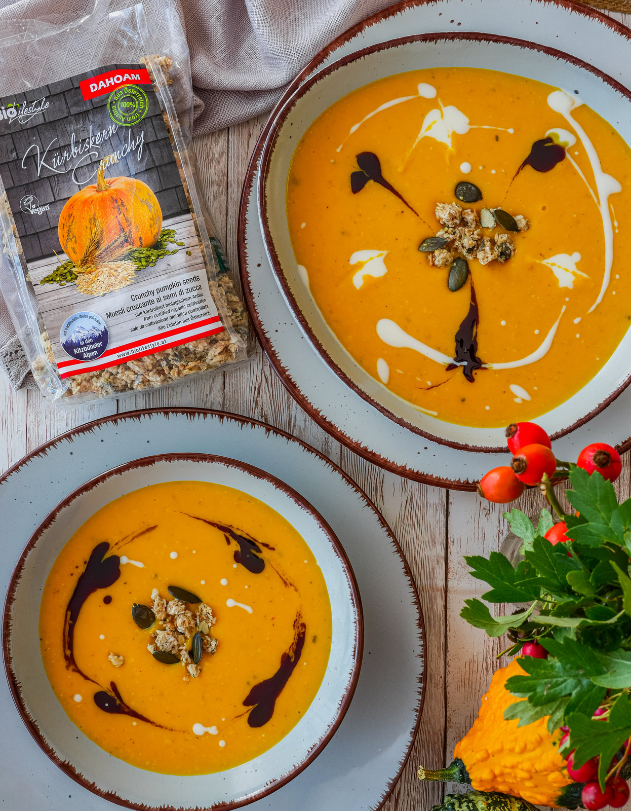 Cremige Kürbissuppe in einer Schale, garniert mit Kürbiskernöl und Kürbis-Crunchy