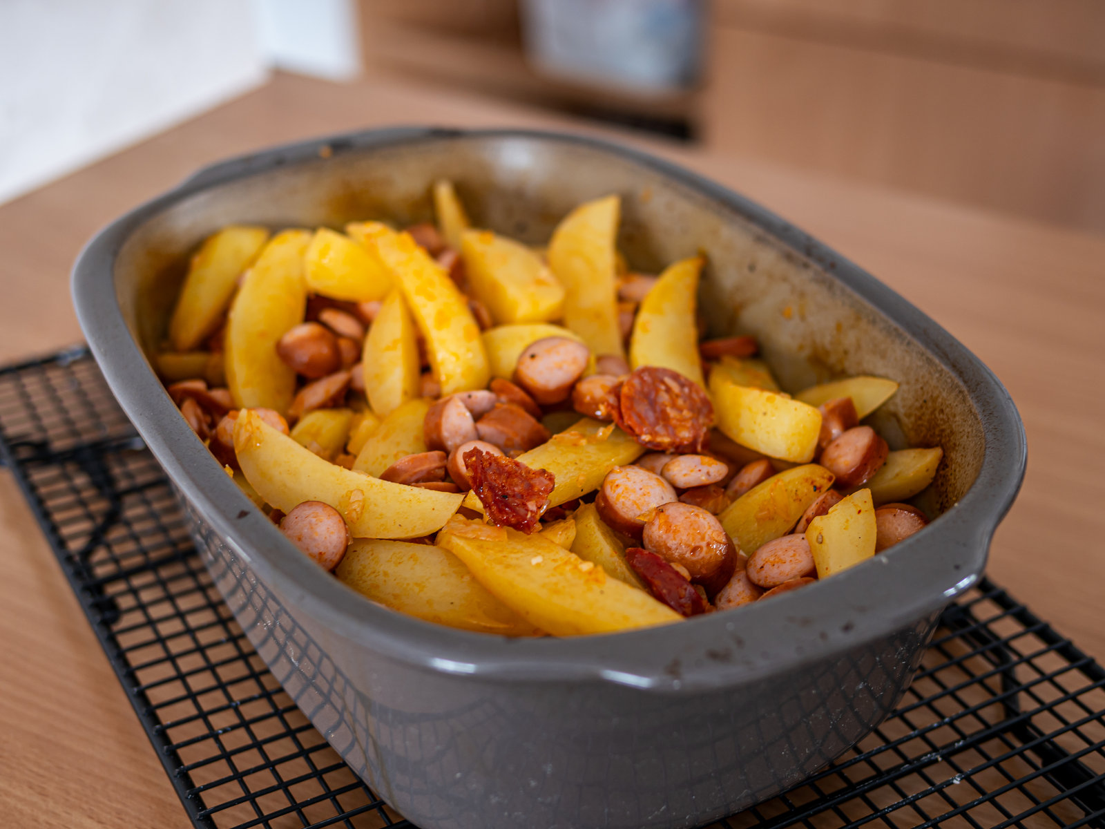 Fertiges Kartoffelgulasch mit Wurst und Kartoffeln in einer Auflaufform, garniert mit frischen Kräutern.