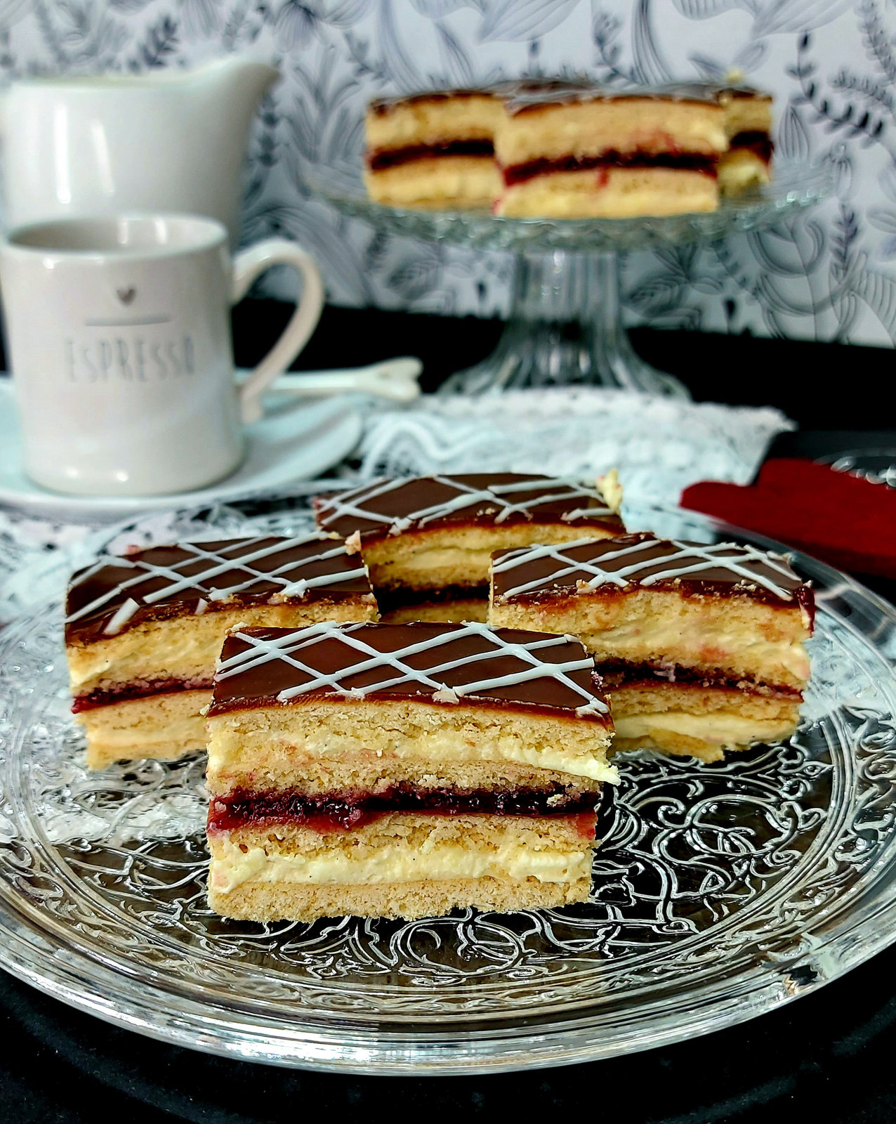 Ein Stück Honigkuchen mit Vanillecreme, Waldbeermarmelade und Schokoglasur