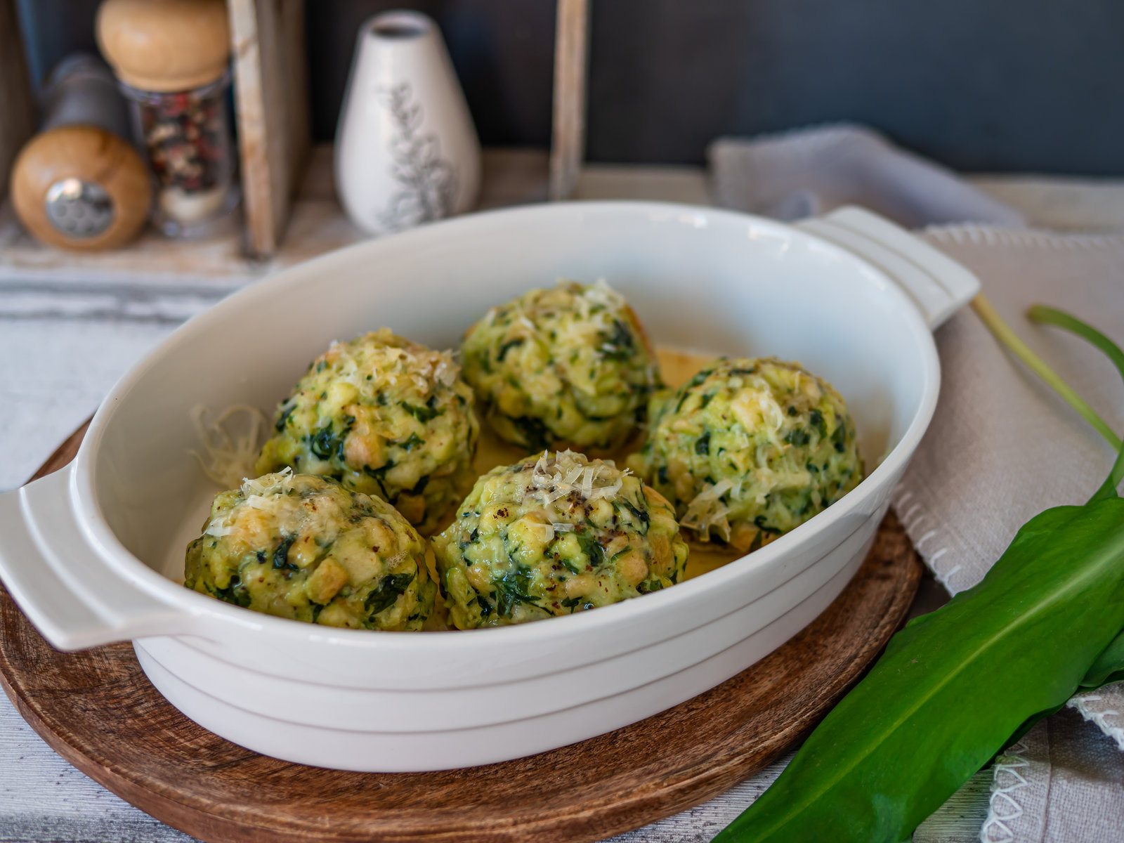 Bärlauchknödel mit brauner Nussbutter und geriebenem Käse auf einem Teller