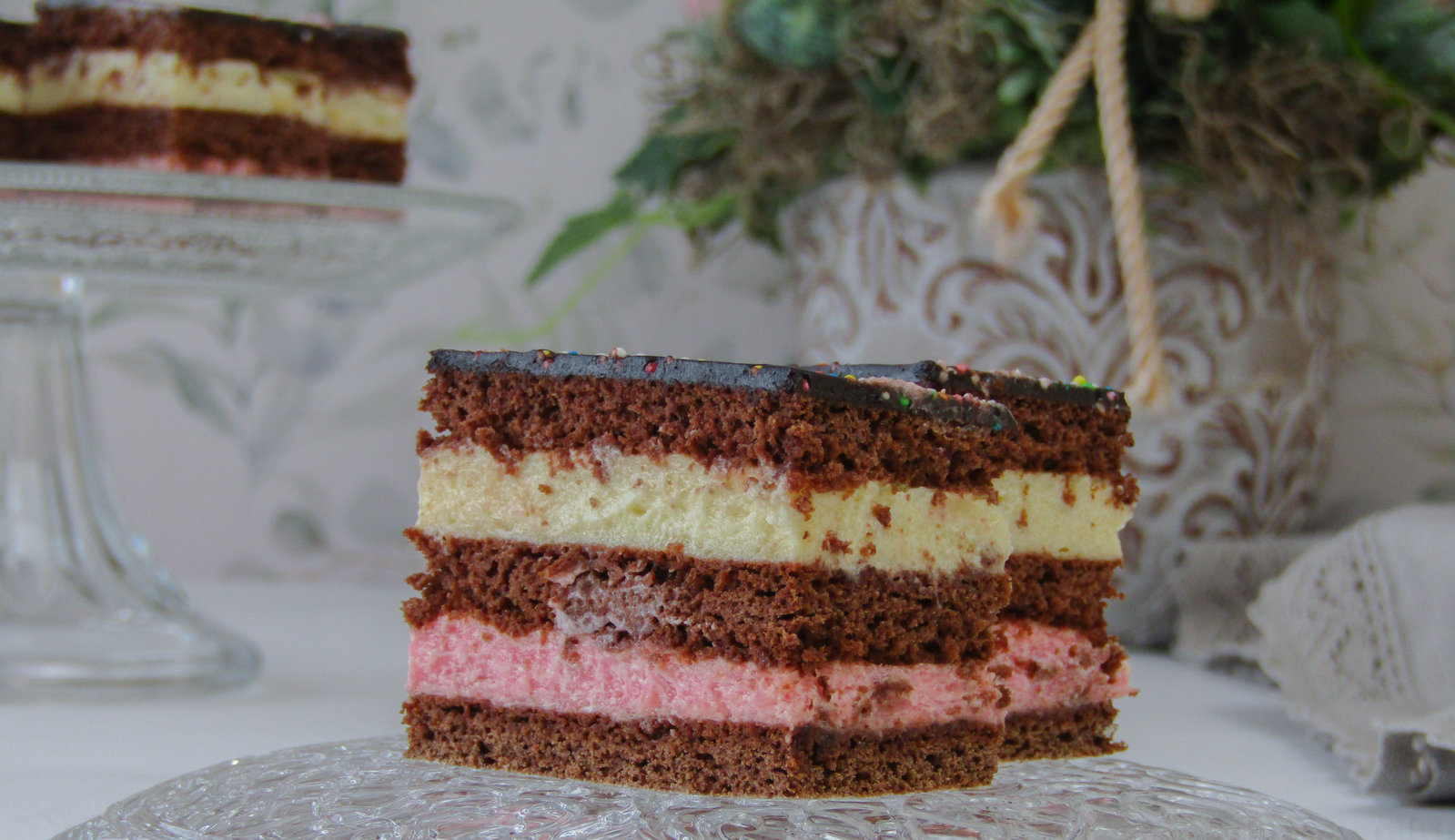 Anschnitt einer Ludwig Schnitte mit mehreren Schichten Teig und Creme, bedeckt mit Schokoladenglasur und Zuckerstreuseln.