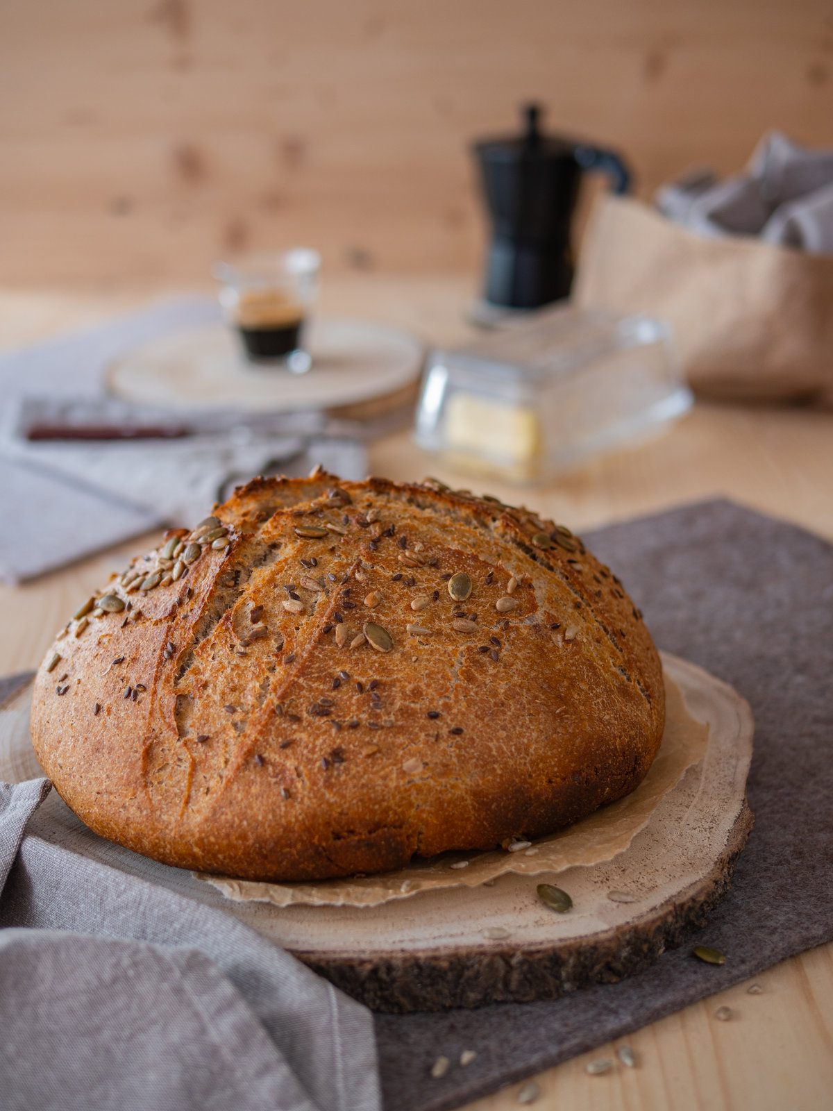 Ein frisch gebackenes, rundes Quarkbrot mit goldbrauner Kruste und Kernen auf einem Gitterrost.