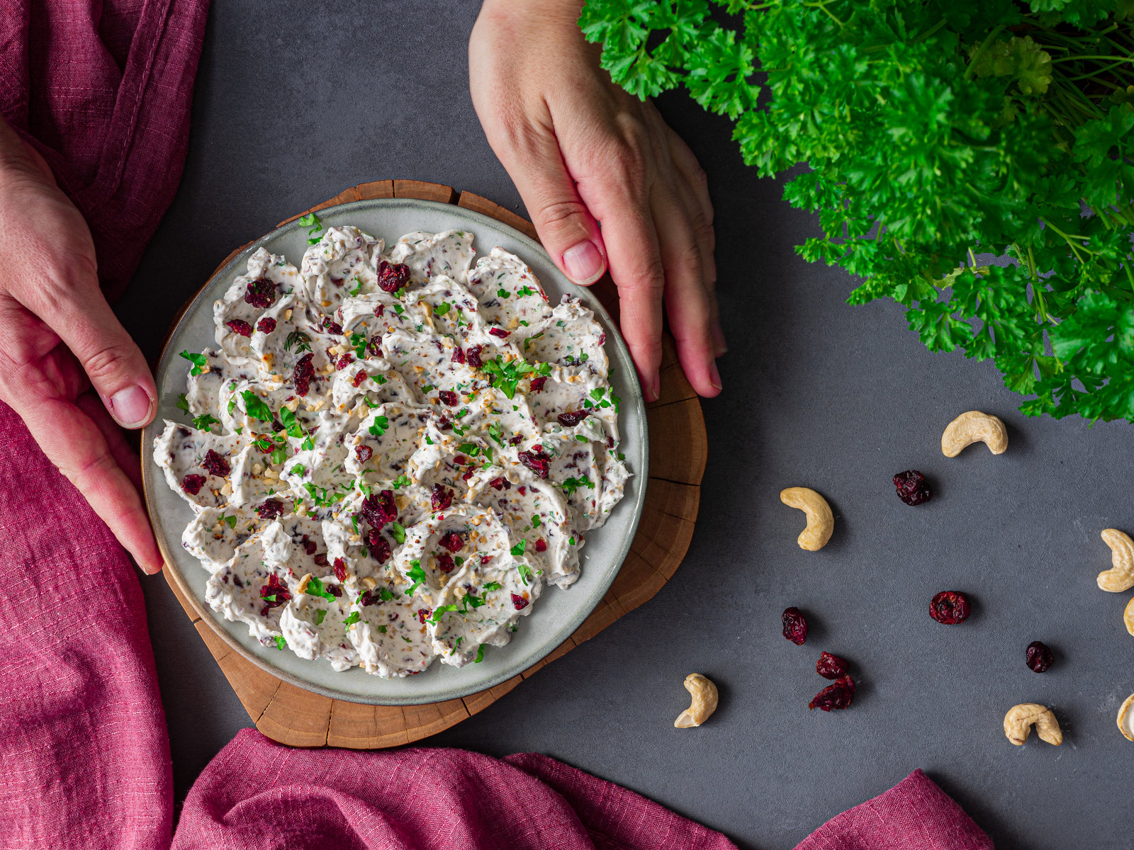 Cremiger Ziegenfrischkäse-Aufstrich mit Cranberrys und Cashewkernen in einer Schale, daneben Brot.