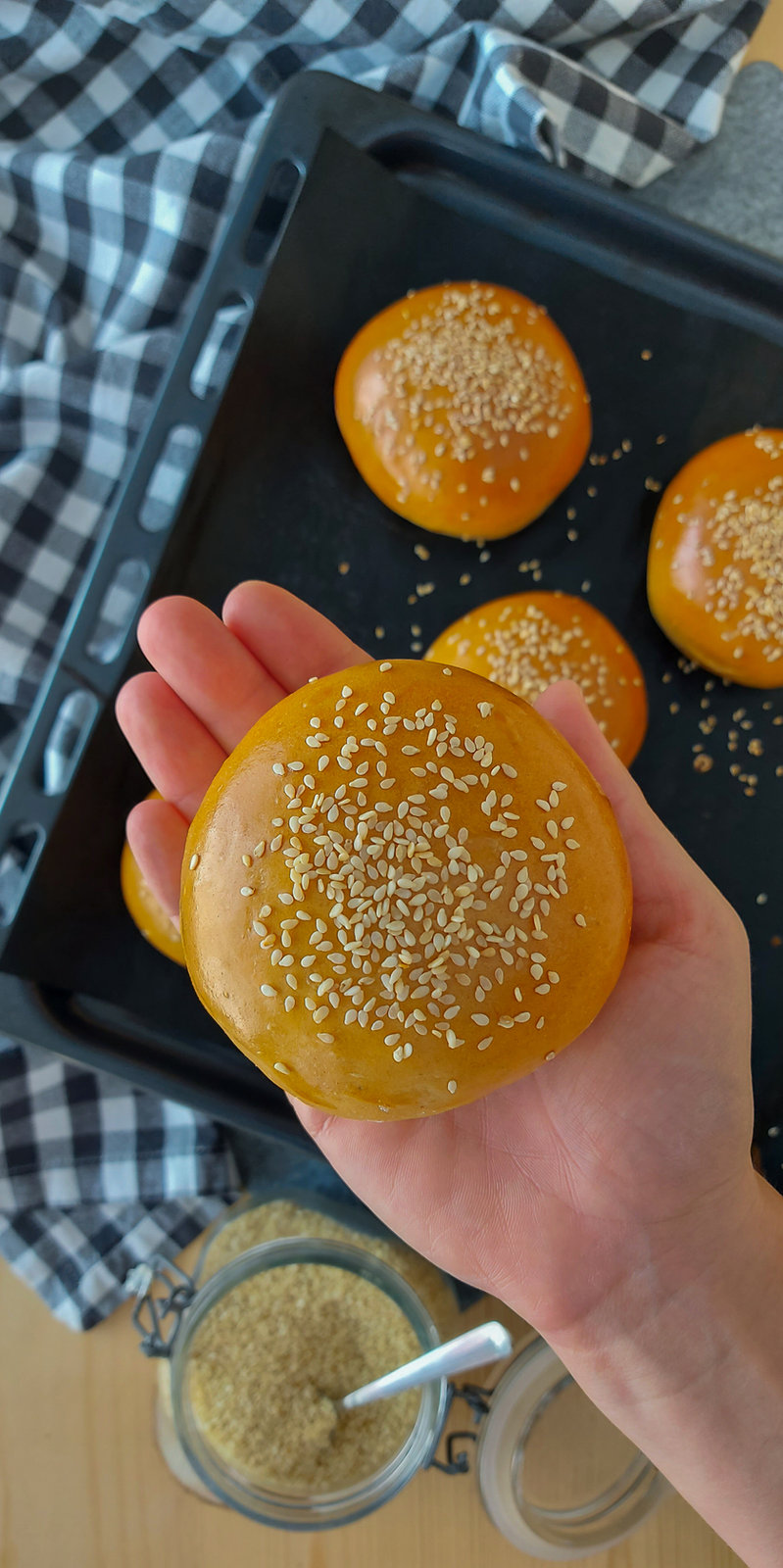 Frisch gebackene Dinkel-Weizen-Burger-Brötchen mit Sesam bestreut auf einem Backblech.