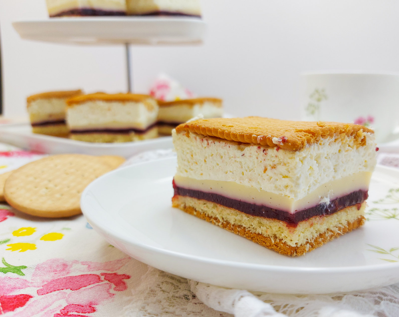 Ein angeschnittener Butterkeks-Kuchen mit mehreren Schichten aus Keksboden, Marmelade, Vanillecreme und Sahne, bedeckt mit Butterkeksen.