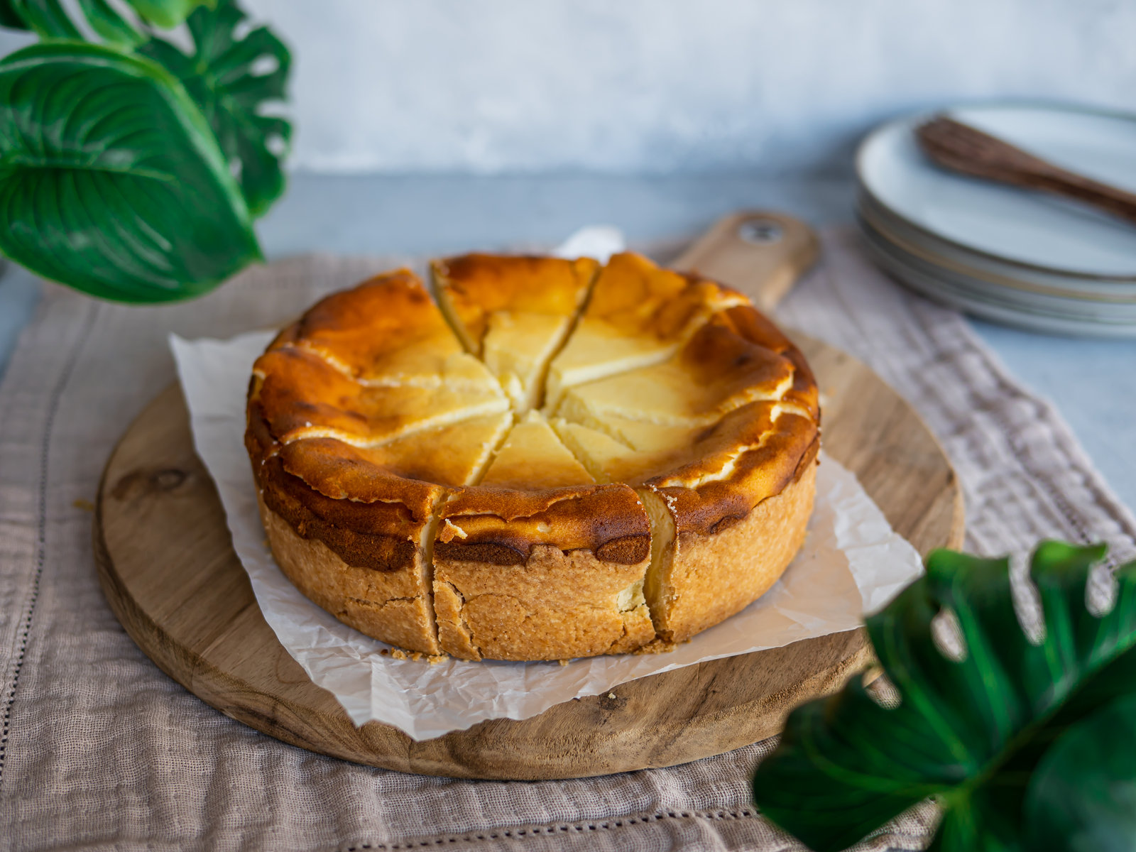 Ein Stück Käsekuchen mit Mürbteig auf einem Teller, daneben eine Gabel.