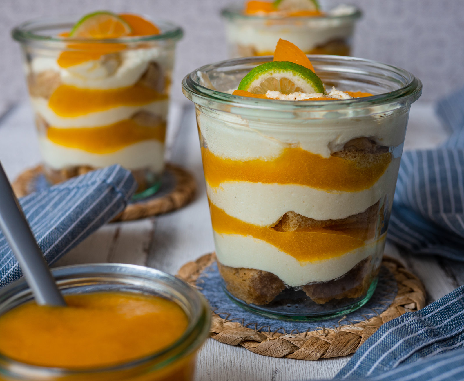 Pfirsich-Tiramisu im Glas, geschichtet mit Löffelbiskuit, Mascarponecreme und Pfirsichpüree, dekoriert mit frischen Pfirsichstücken und Minze.