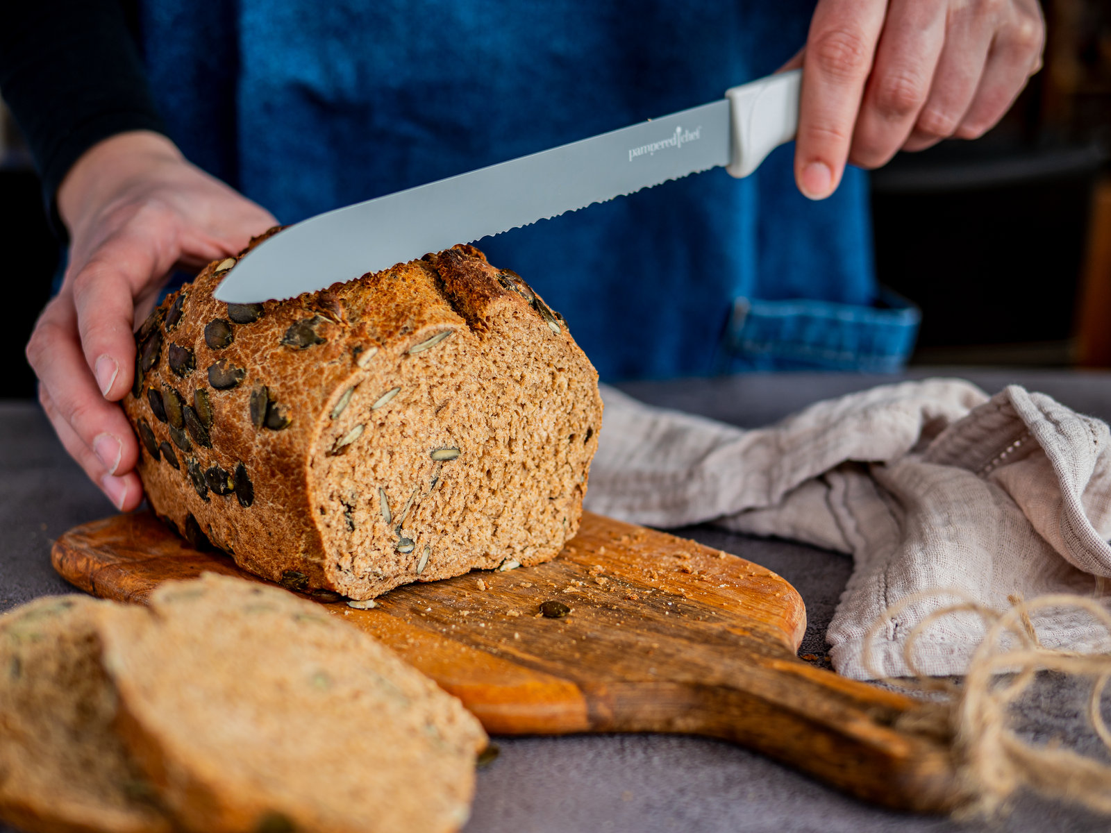 Ein frisch gebackenes Vollkornbrot mit Kürbiskernen, angeschnitten auf einem Holzbrett.