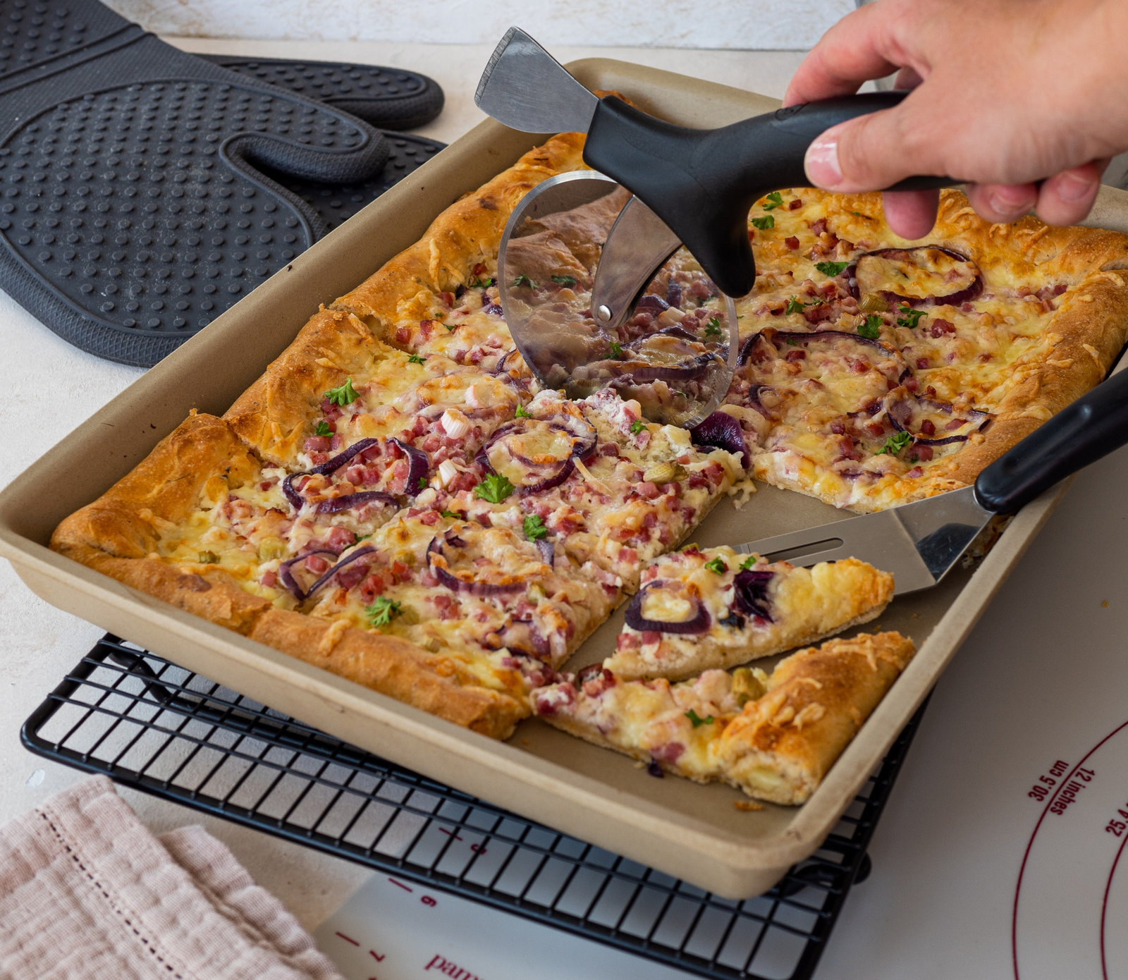 Ein fertig gebackener Dinkelflammkuchen mit hellem Boden und goldbraunem Belag, frisch aus dem Ofen.