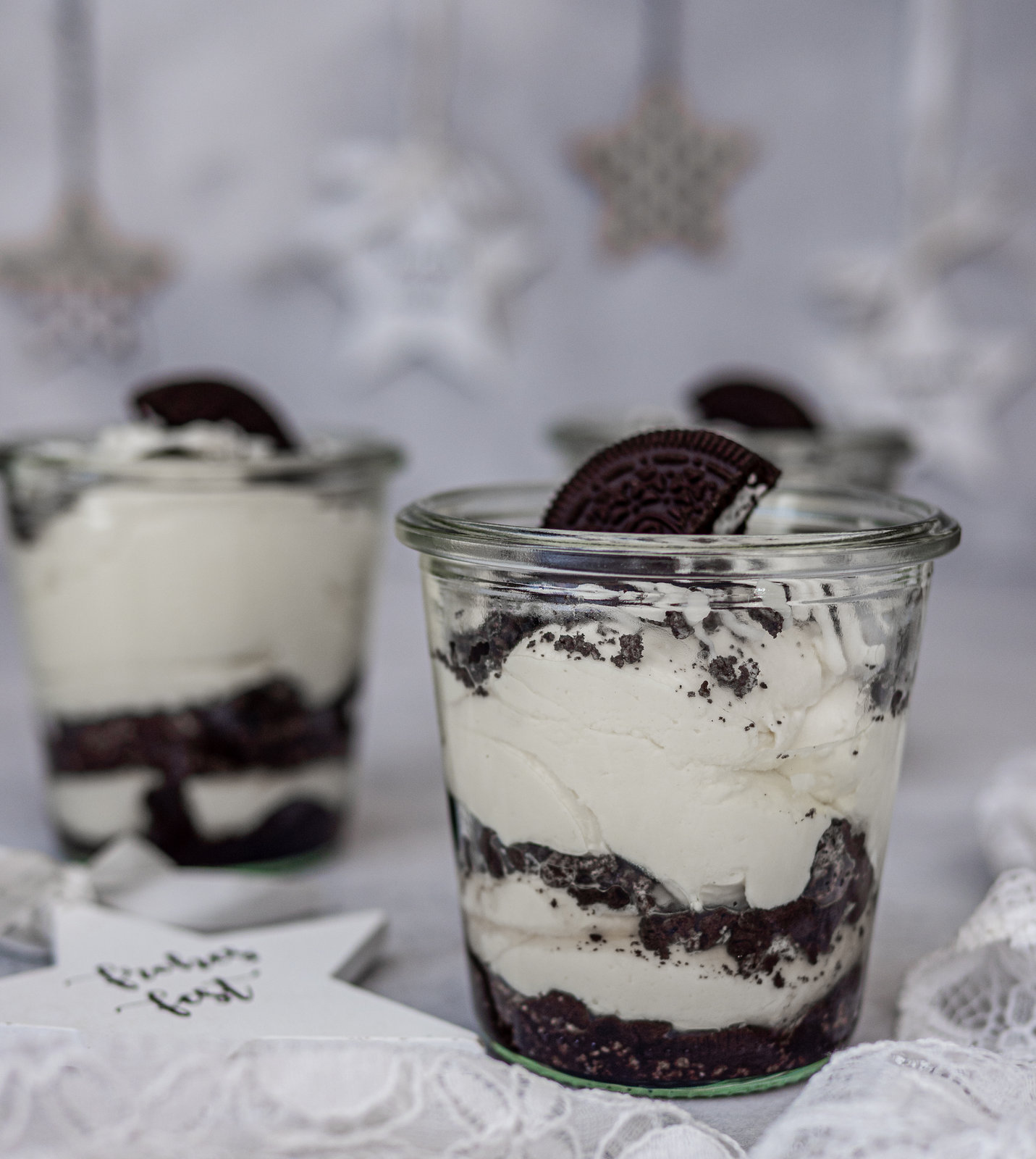 Oreo Glasdessert in kleinen Gläsern, geschichtet mit Creme und Keksstücken, dekoriert mit halben Oreo Keksen.