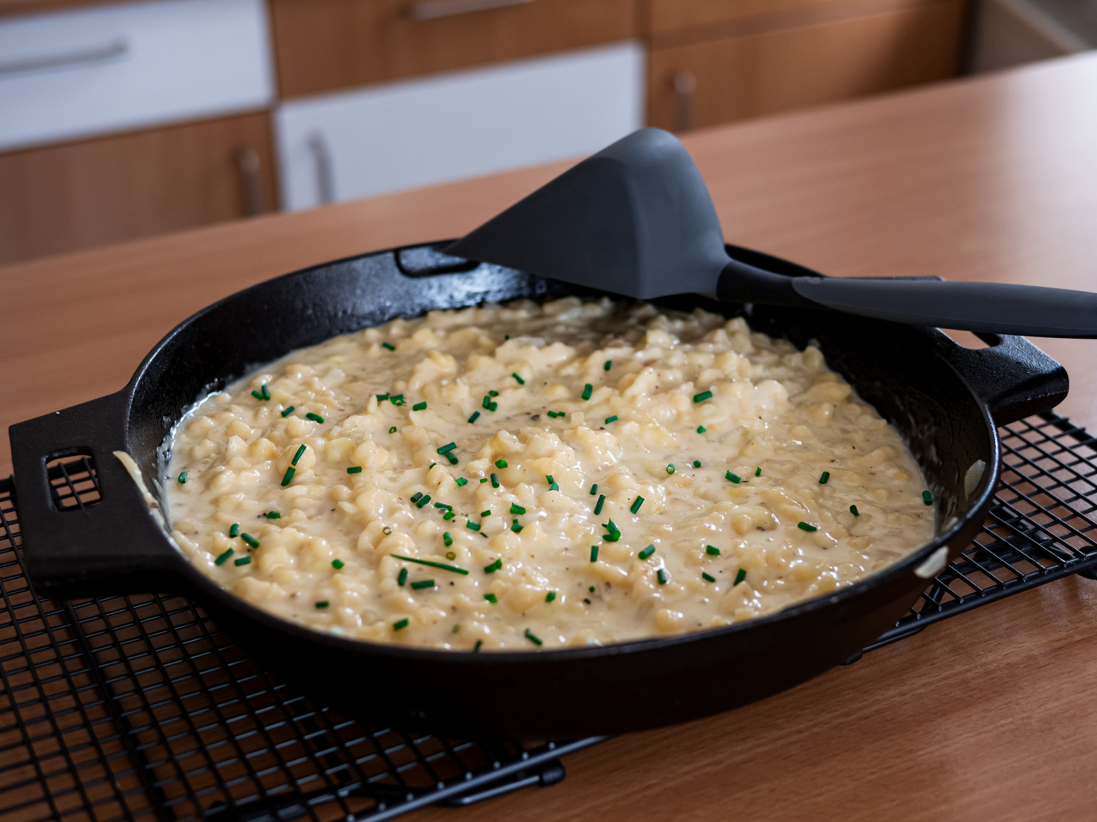 Käsespätzle mit Röstzwiebeln und Schnittlauch in einer gusseisernen Pfanne