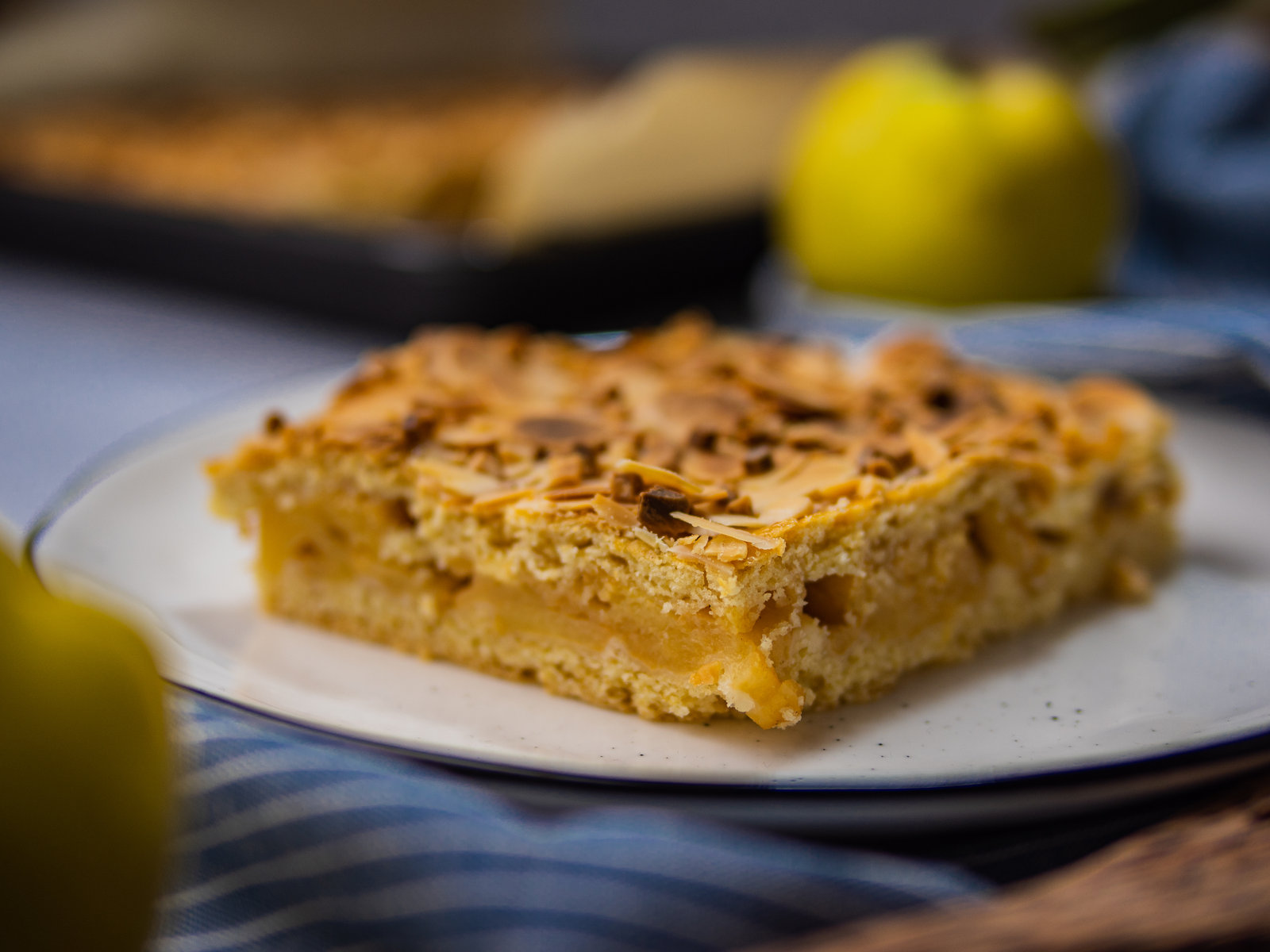 Ein Stück Quittenkuchen auf einem Teller, bestreut mit Puderzucker.