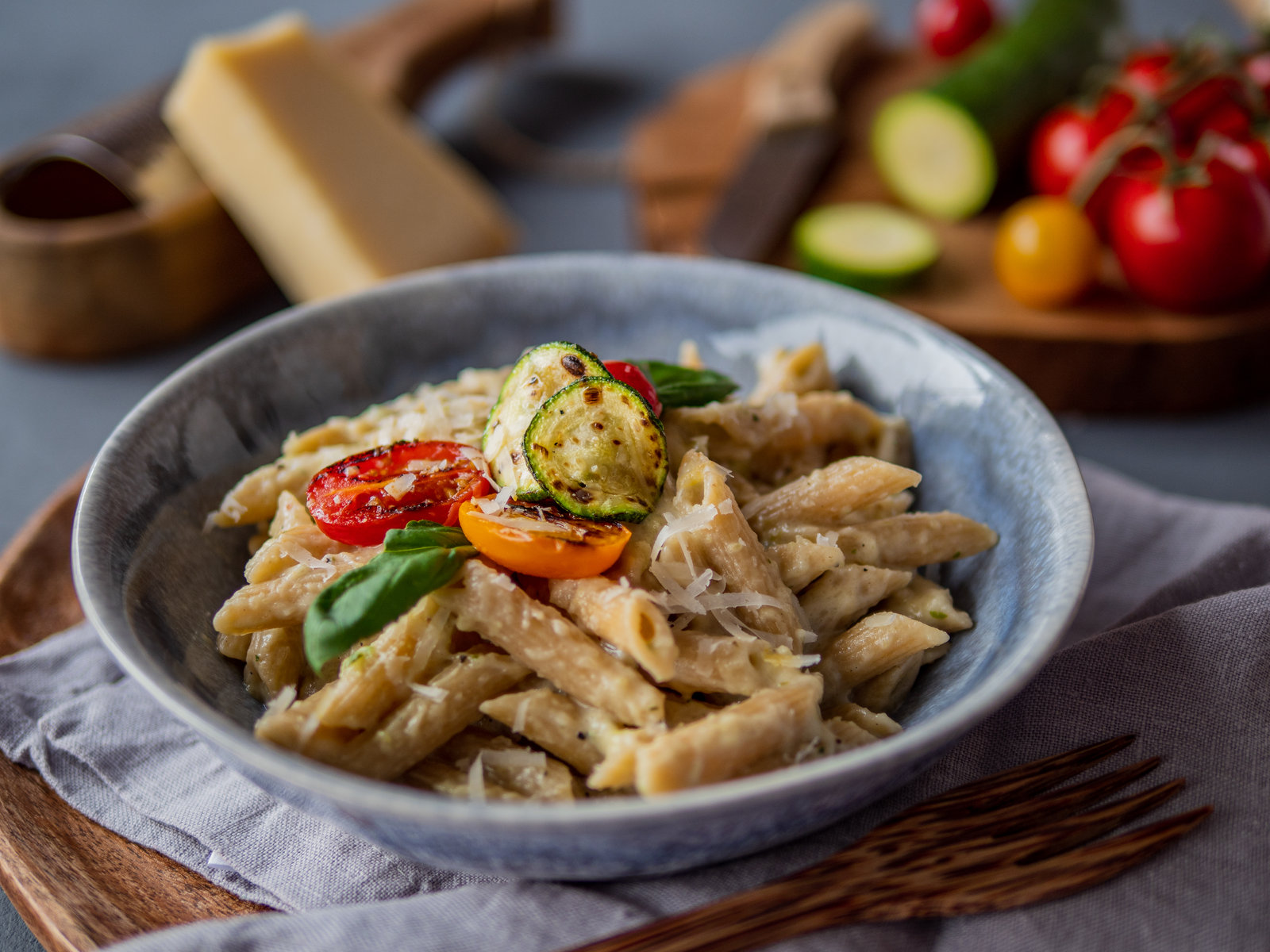 Nudeln mit cremiger Zucchini-Käse-Sauce, garniert mit Basilikum und Tomaten